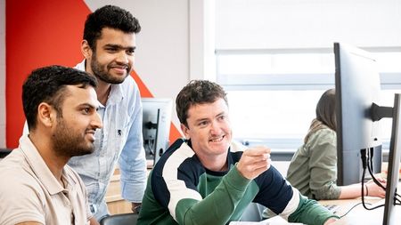 Three students working on computer in NCI classroom 